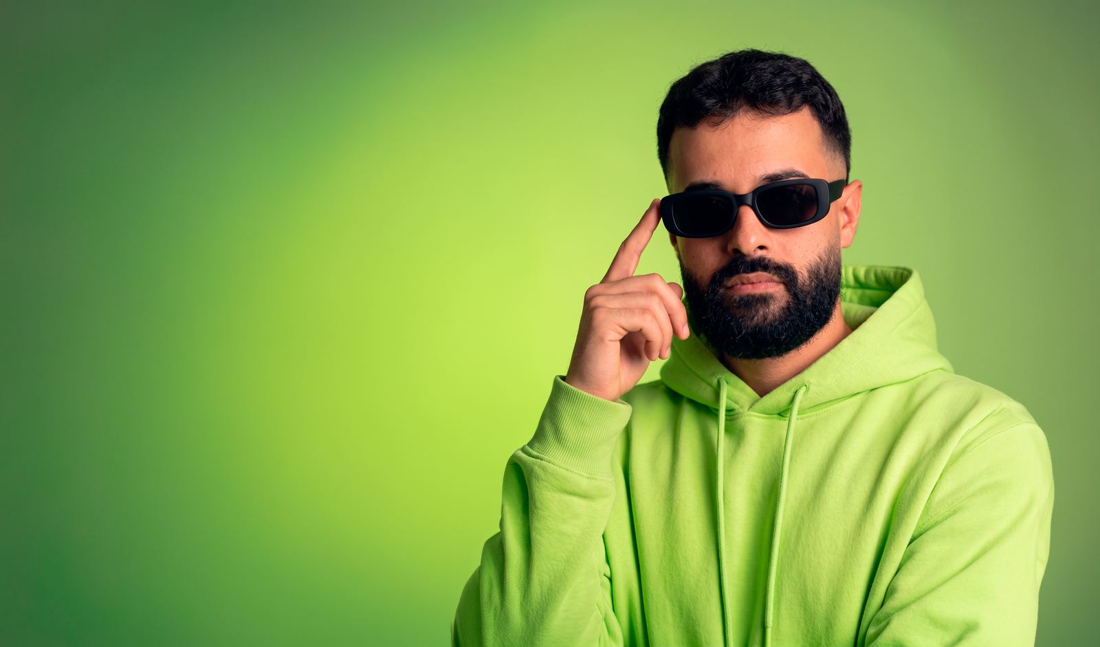 Israel Meira de moletom lime e óculos escuros, com o dedo na têmpora