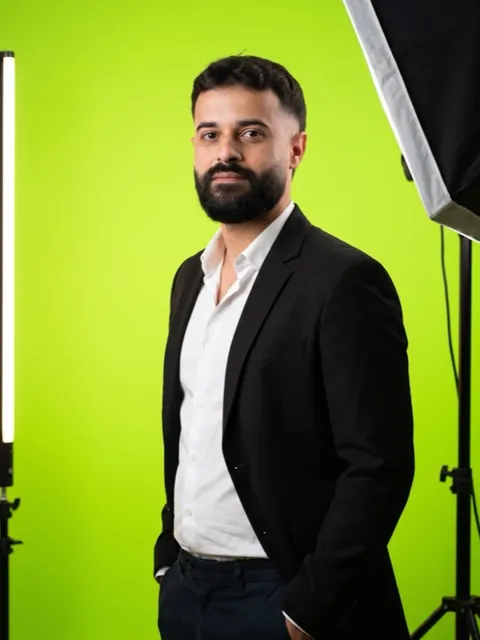 Exemplo de foto 2: Israel Meira de blazer, da cintura para cima, num estúdio de fundo verde