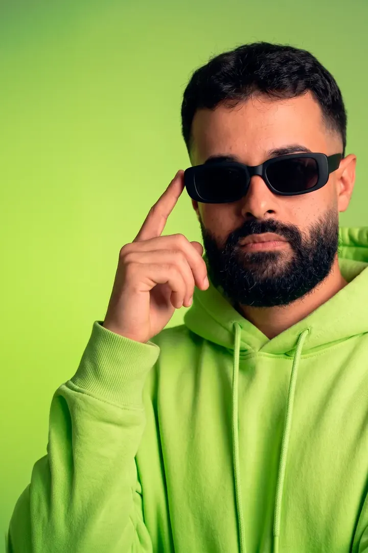 Israel Meira de óculos escuros e moletom verde, sobre fundo verde